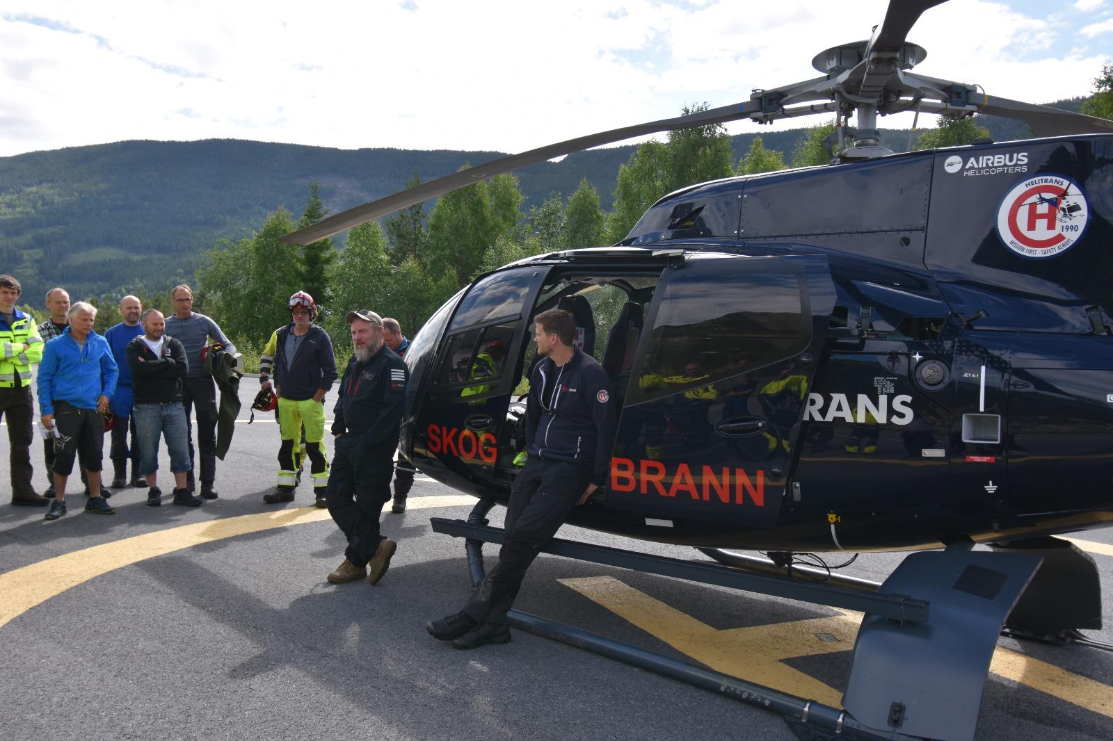Wildfire response personnel gathered beside a firefighting helicopter